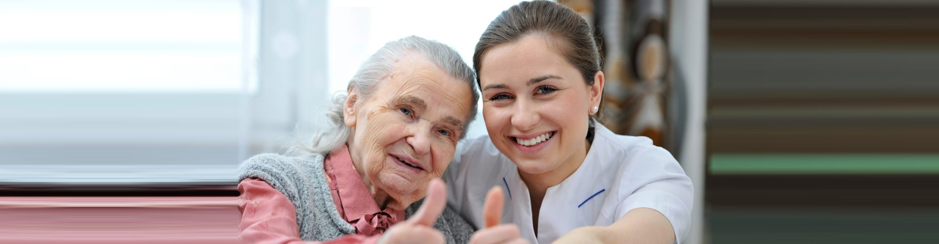 caregiver and senior woman giving thumbs up