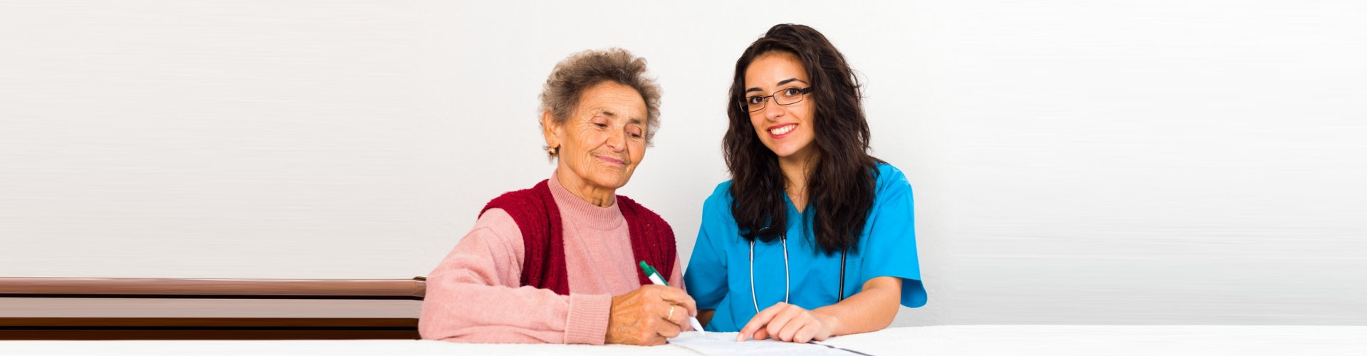 caregiver assisting the senior woman to write